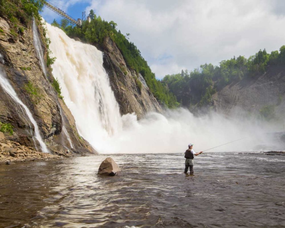 A fly fisherman casts his line at the base of Montmorency Falls in Quebec City