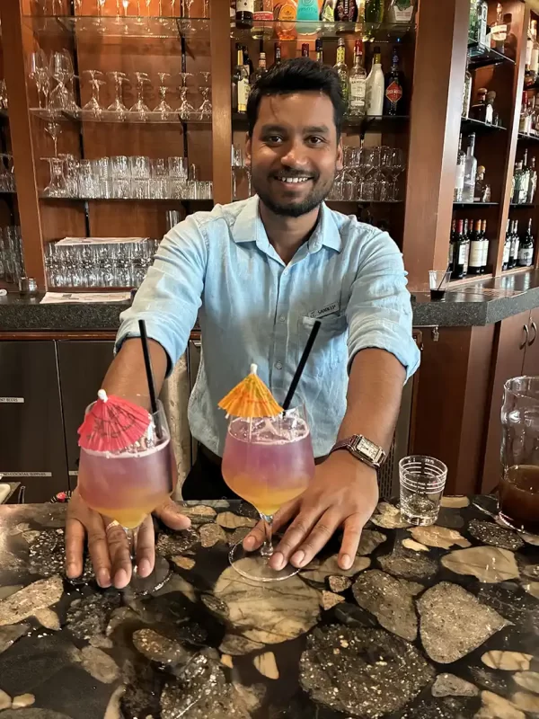 A bartender pushes two cocktails glasses across a bar at Elk Ridge Resort