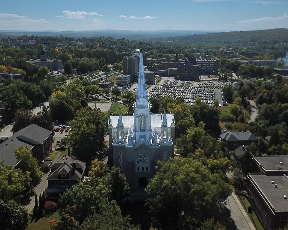 Aerial photo of a church in Sherbrooke, Quebec poking out of a grove of trees