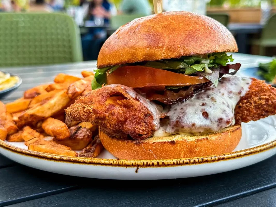 A fried chicken sandwich covered in melted cheese with a side of French fries from A l'Abordage craft brewery in Bromont, Quebec